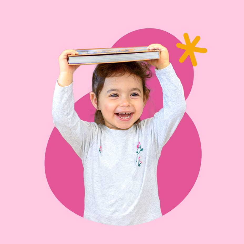 Young girl smiling and balancing a book on her head